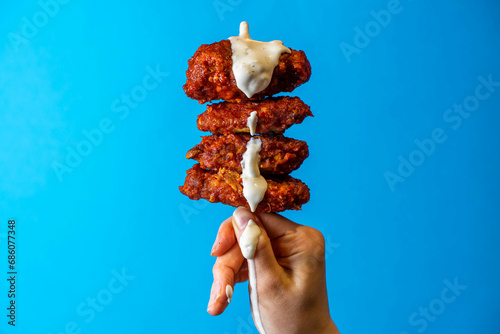 Fried Chicken Hot Wing Being Dipping With Cool Ranch Sauce, Royal Blue Background, Editorial Creative Food Photography 