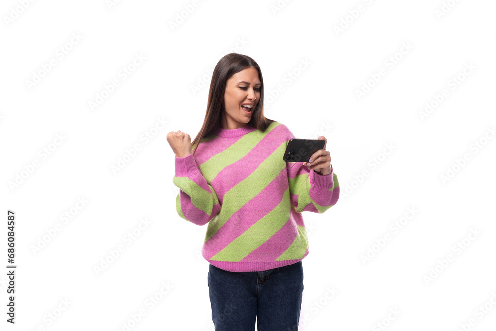 pretty young brunette woman in a striped pink blouse watching video on a smartphone on a white background with copy space