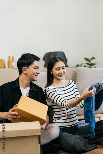 Young couple relaxing sitting on the floor around cardboard boxes at home, smiling happy moving to a new house. © NINENII