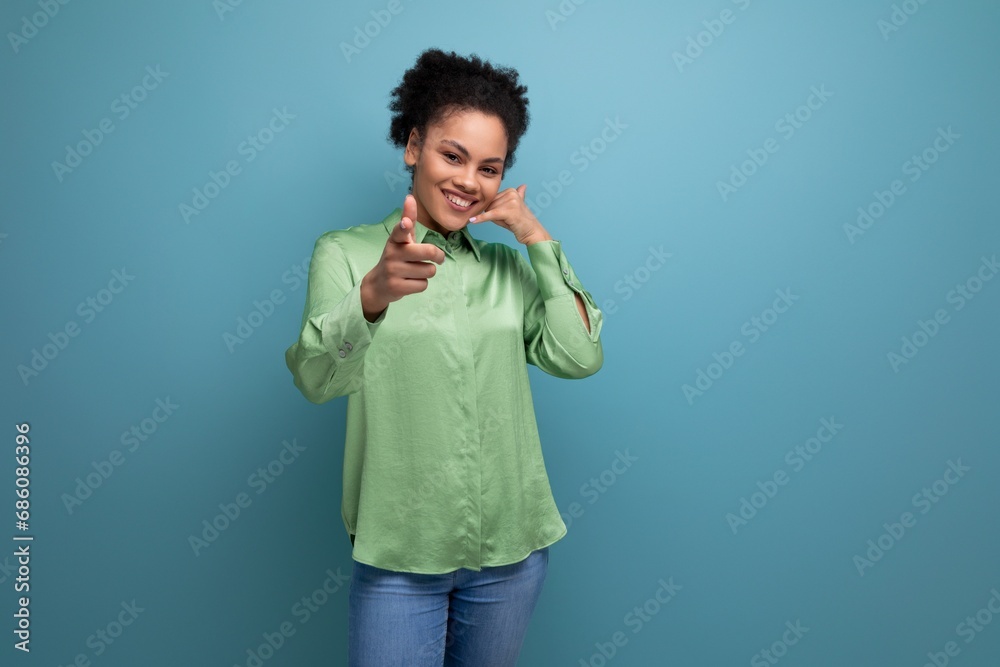 young female model with curly black hair dressed in a green blouse points with her hand at an advertisement on an isolated background with copy space young female model with curly black hair dressed in a green blouse points with her hand at an advertisement on an isolated background with copy space