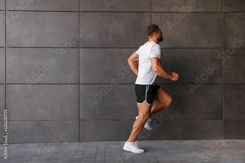 Young man running near building outdoors. Space for text