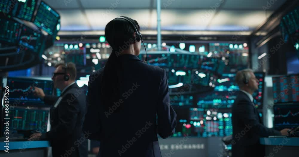 Young Asian Female Broker Working on Tablet Computer on Stock Exchange Floor. Traders Monitoring Real-Time Stocks, Commodities and Exchange Market Data. Professional Investment Agents in Office