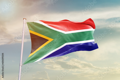 South Africa national flag waving in beautiful sky. The symbol of the state on wavy silk fabric.