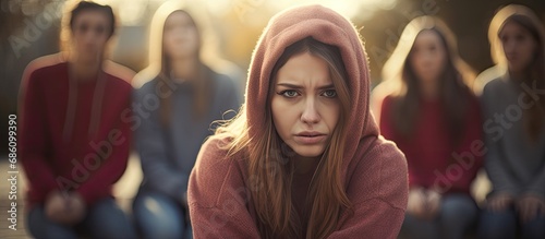 Teenage girl in hoodie participating in diverse group therapy session. photo