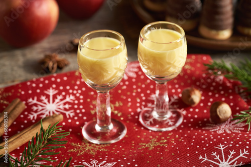 Eggnog in two small glasses with apples and Christmas cookies photo