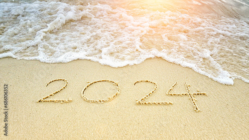 happy new year 2024. number 2024 write on sandy beach with ripple ocean wave splash with white bubble. countdown for happy new year turning from year 2023 to 2024 background