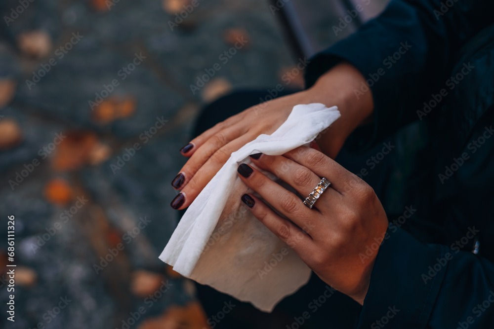 Obraz premium Woman wipes her hands on the street with a damp cloth. The girl disinfects her hands with napkins and alcohol. 