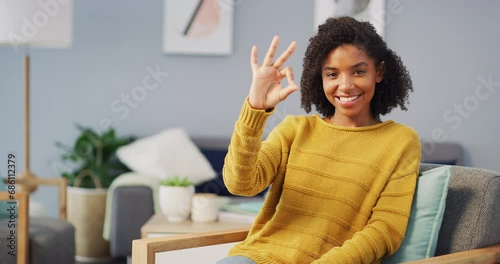 Face, smile and woman with perfect hands, wink or smile on a chair with good mood, attitude or positive mindset. Okay, emoji and portrait of female person in living room with vote, sign or feedback photo