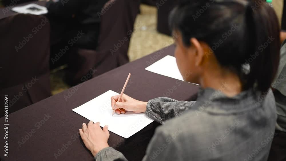 A woman uses a pen to write notes on the desk in the office room. A woman uses a pen to write notes on the desk in the office room.