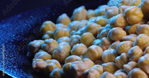 Lots of  boiled chickpeas rotate on a black plate on a blue background.