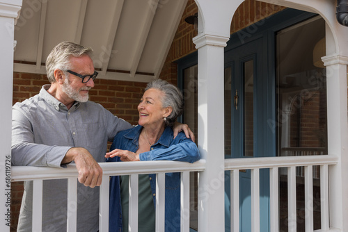 Happy senior couple standing in porch smiling together photo
