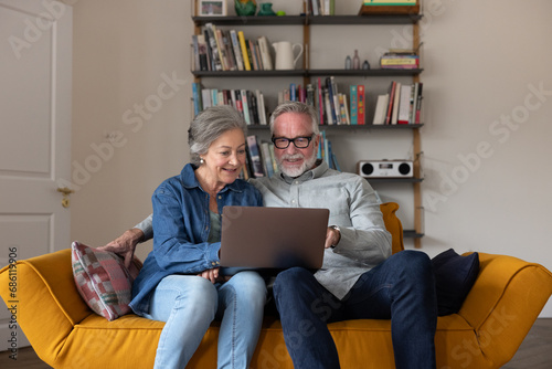 Senior couple at home looking at a laptop happily