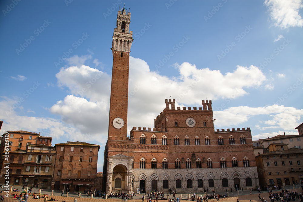 Tourists at Piazza del Campo and Palazzo Comunale, with er historic buildings in Siena, Italy
