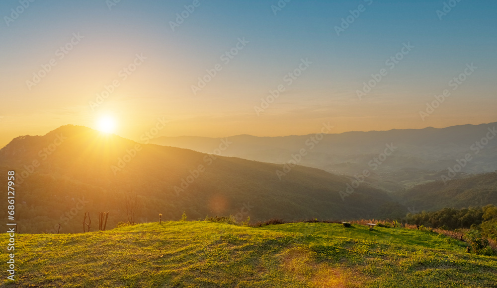 Grass field and mountains view with sunset sky background. countryside landscape
