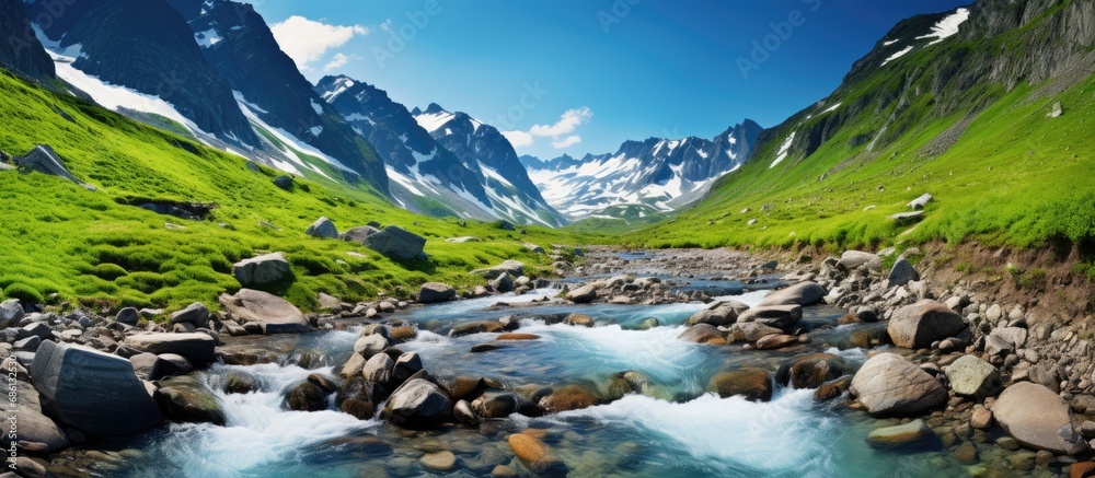 Summer mountain stream amid melting glacier rocks.