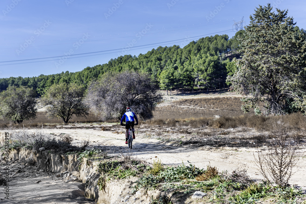 A cyclist crossing a sandy road with his dirt bicycle