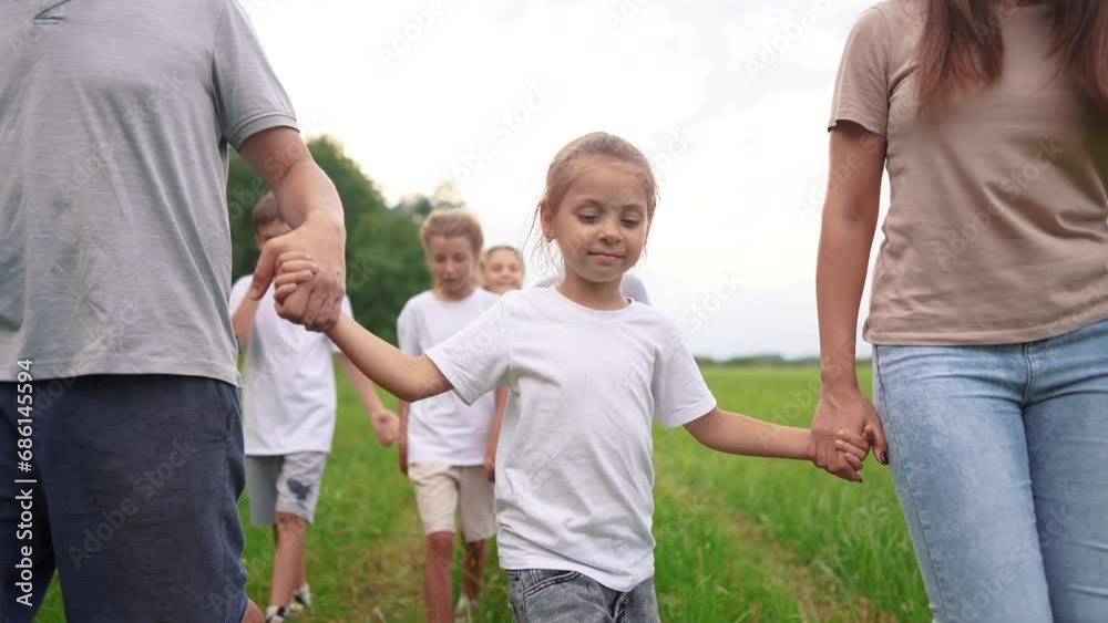 family walking on the grass in the park and holding hands. happy family childhood dream concept. a large family walks across the lifestyle clearing and talks to each other. outdoor nature walk family walking on the grass in the park and holding hands. happy family childhood dream concept. a large family walks across the lifestyle clearing and talks to each other. outdoor nature walk