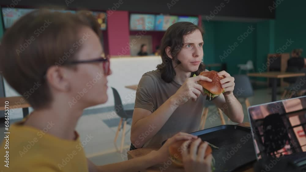 a group of students sit in a cafe and do lifestyle a project on a laptop together. business concept of modern training and development. students discuss their homework and eat fast food burgers a group of students sit in a cafe and do lifestyle a project on a laptop together. business concept of modern training and development. students discuss their homework and eat fast food burgers