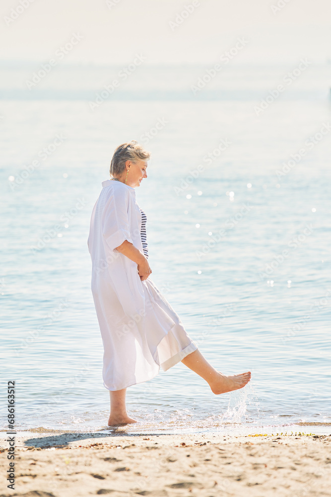 Outdoor summer portrait of happy and healthy mature 50 - 55 year old woman enjoying nice sunny day by the lake or sea, active lifestyle Outdoor summer portrait of happy and healthy mature 50 - 55 year old woman enjoying nice sunny day by the lake or sea, active lifestyle