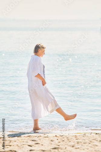Outdoor summer portrait of happy and healthy mature 50 - 55 year old woman enjoying nice sunny day by the lake or sea, active lifestyle © annanahabed
