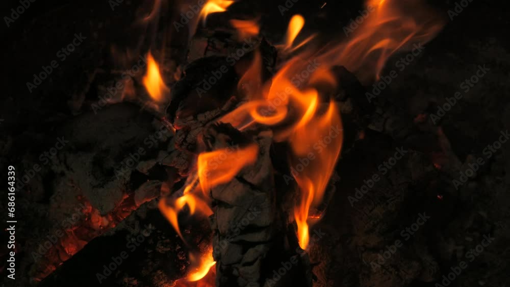 Incredibly beautiful bonfire flame in slow motion. Flames on a wooden log in a bonfire at night. Active lifestyle, traveling, hiking and camping concept. Campfire burning in slow motion.