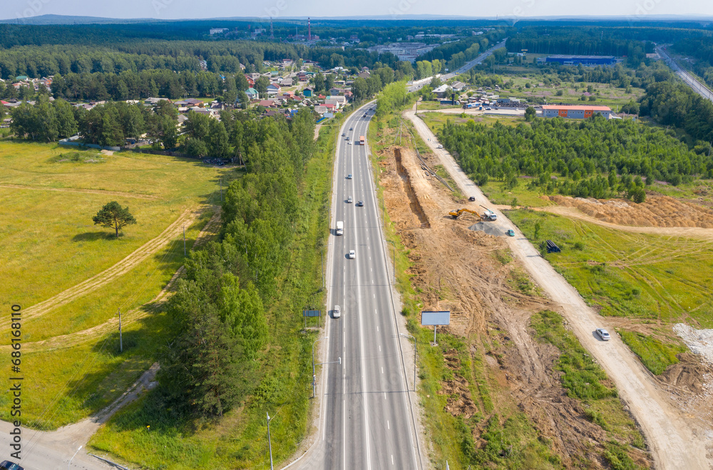 Top view of the movement of cars on the motorway through the forest