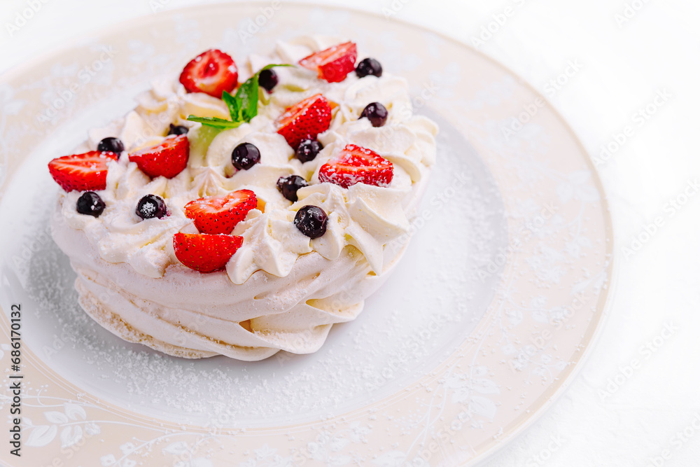 Pavlova cakes with cream and fresh berries on plate