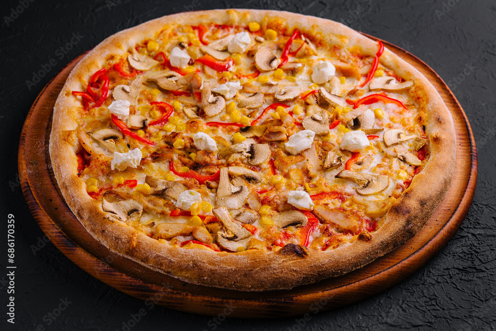 pizza with bell peppers, corn, meat and mushrooms on wooden board
