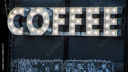 Coffee stall at a Christmas market. Black background with big white illuminated lights advertising hot teas and coffee beverages for sale from an independent vendor at a market square. photo