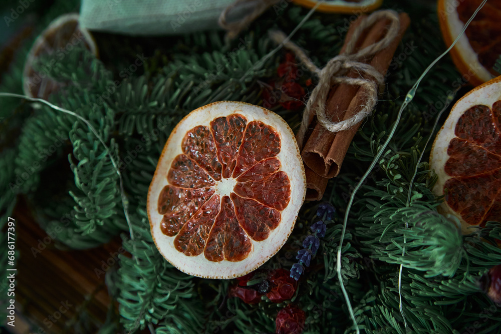 Dried orange on the background of a pine branch. New Year's mood and aromas, interior decoration. Festive Christmas decor.