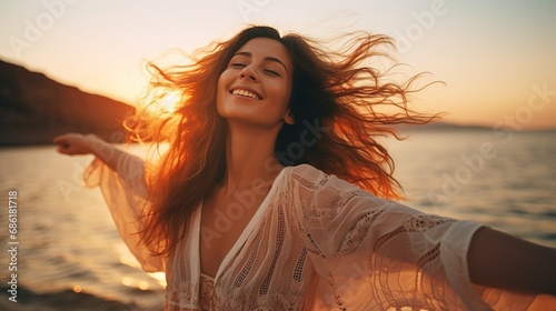 Portrait of calm happy smiling free woman with open arms and closed eyes enjoys a beautiful moment life on the seashore at sunset time #686181718