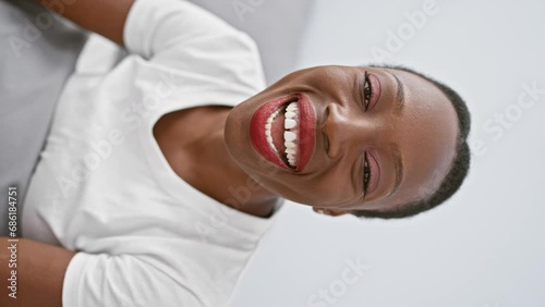 Attractive african american woman lying on her comfy bedroom bed, puffing cheeks in amusing expression, making a crazy funny face, mouth filled with air photo