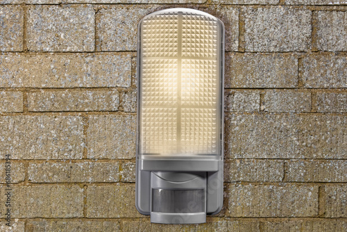 A close up of a PIR Security light fixed to a stone wall with copy space