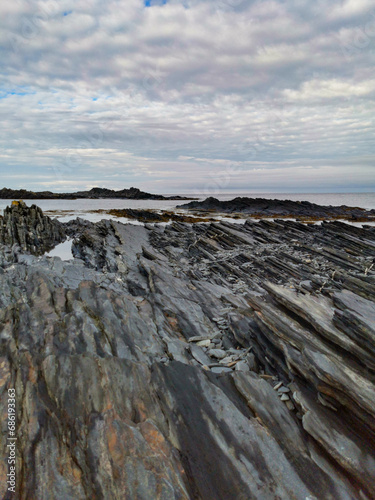 The rocky coast of the Barents Sea. Beautiful view of the rocks and the coast of the Rybachy and Sredny peninsulas, Murmansk region, Russia. The landscape is the harsh beauty of the north. photo