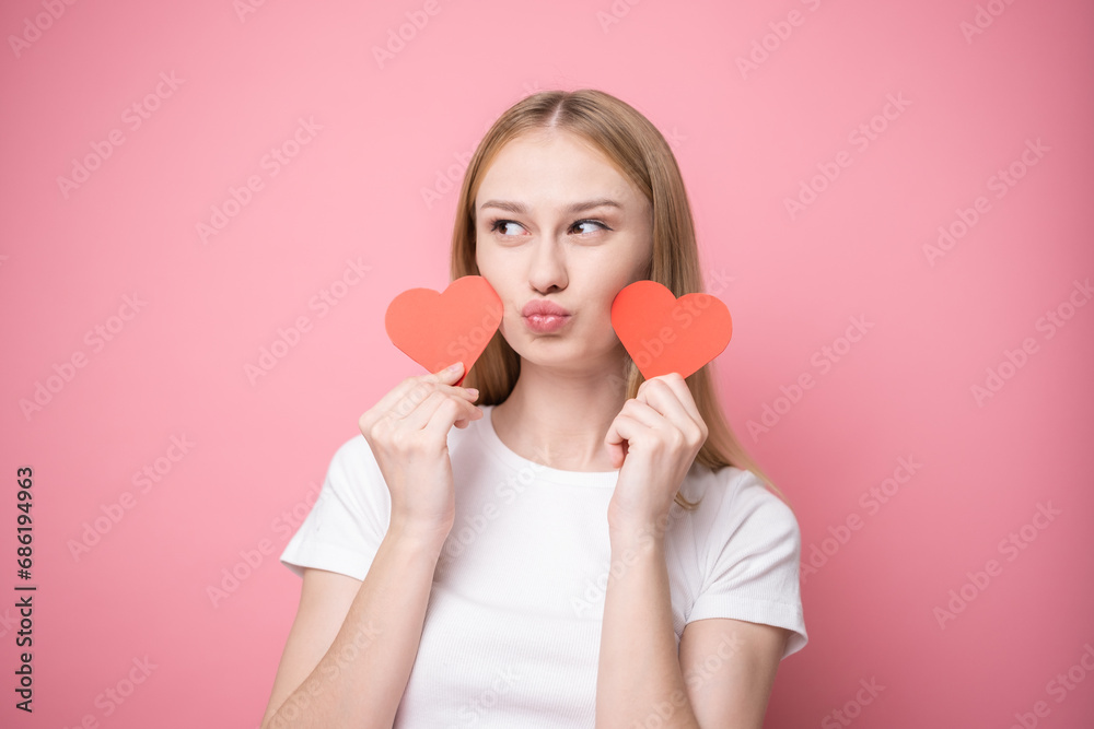 Portrait of attractive girl on pink background with red hearts for valentine's day. Concept of congratulations for holidays. Portrait of attractive girl on pink background with red hearts for valentine's day. Concept of congratulations for holidays.