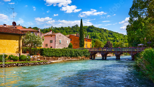 Borghetto Valeggio sul Mincio, Verona, Italy. Italian traditional village with vintage colorful houses above river. Stone bridge among ancient architecture. Flowers and greens. Summer sunny day