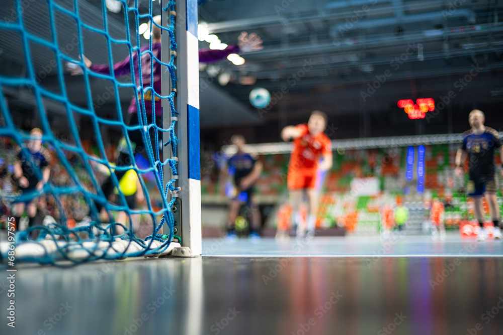 Detail of handball goal post with net and handball match in the background. - obrazy, fototapety, plakaty 