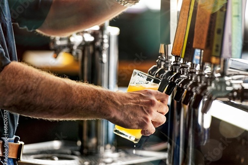 Closeup shot of a male bartender pouring a beer from a tap