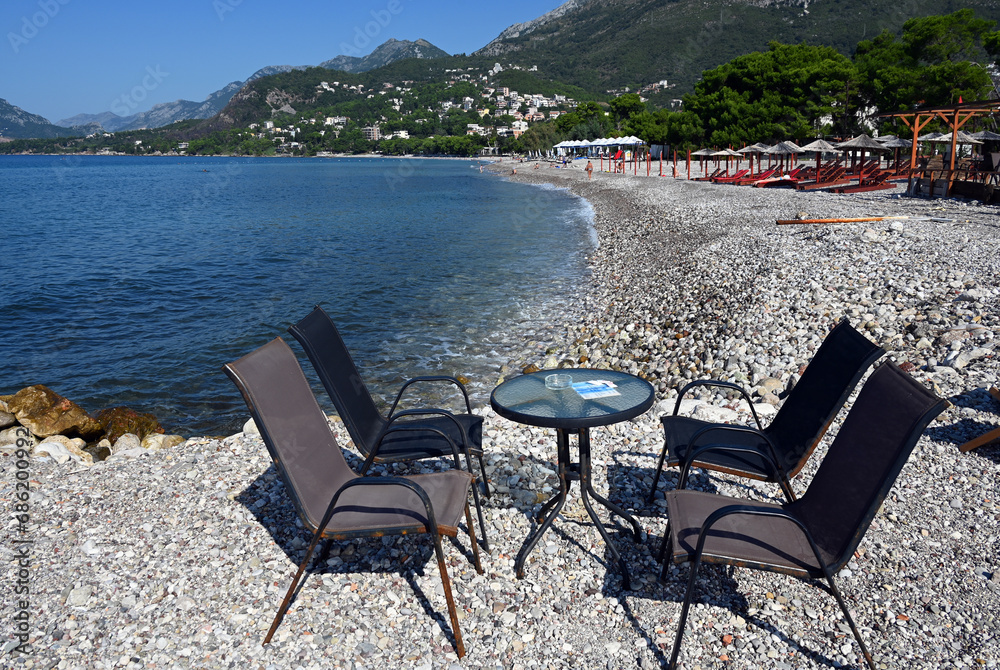 Bar, Montenegro, Dalmatia, Balkans, Europe - chairs and table on characteristic pebbles  beach, Adriatic Sea, Dinaric Alps