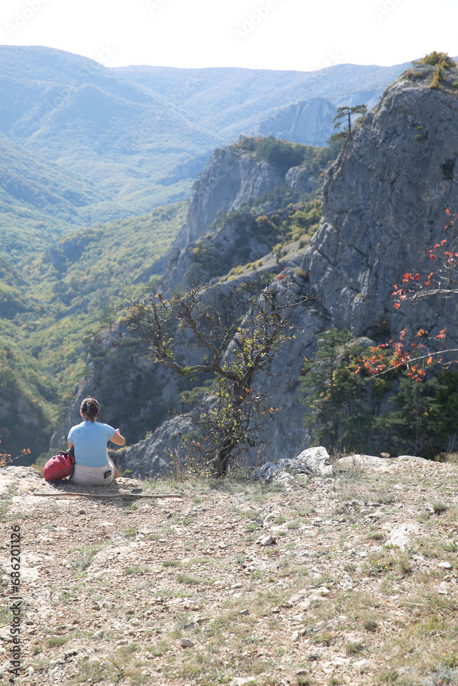 Female hiker sitting on top of mountain and looking at landscape