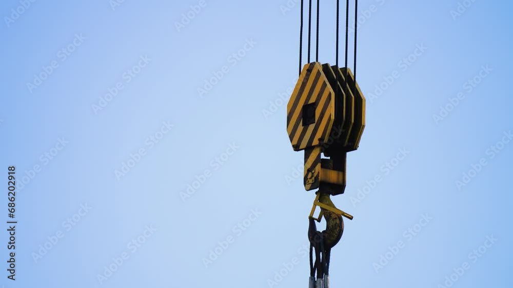 Close up of crane hook on sky background. Parts of construction crane, hook and slings Close up of crane hook on sky background. Parts of construction crane, hook and slings