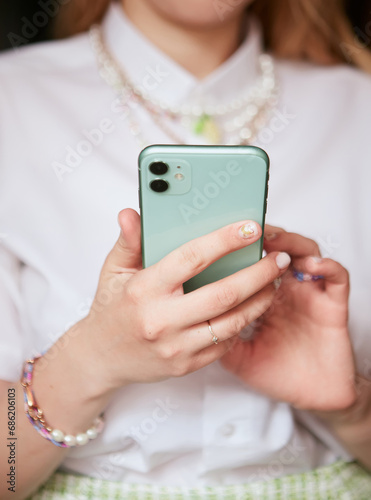 Close view of a girl holding a mint colored phone with the back side in her hands