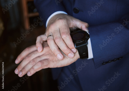 Close-up hands of the man in a dark blue costume with watches