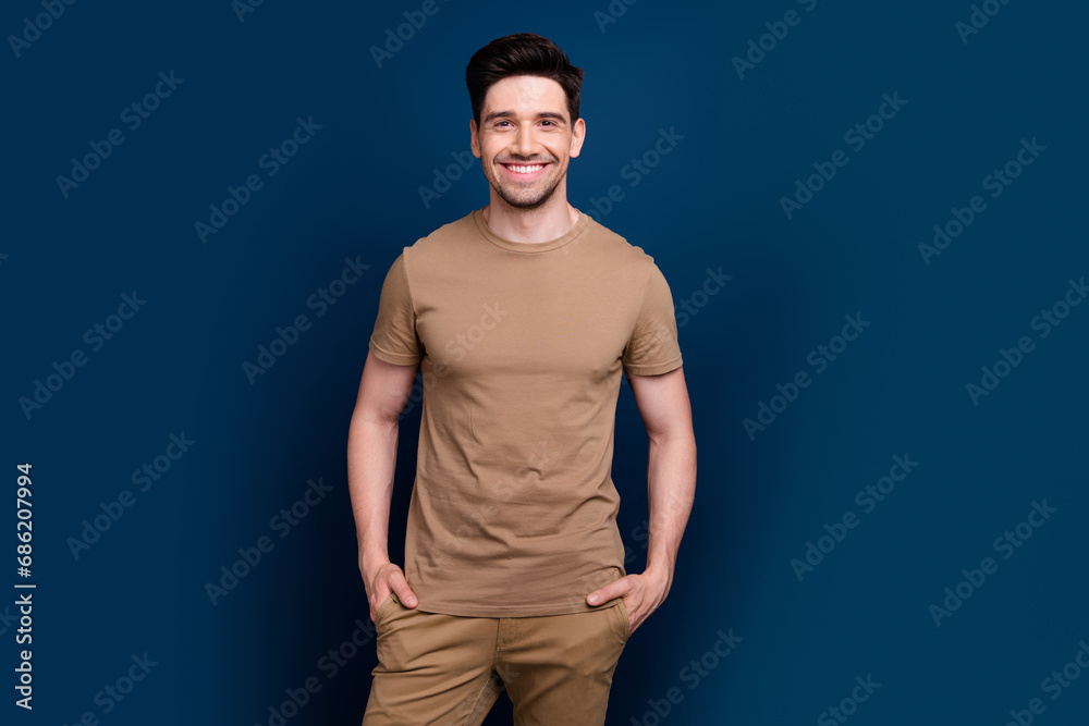 Photo of positive nice man wear beige pastel stylish clothes hands in pockets isolated on dark blue color background