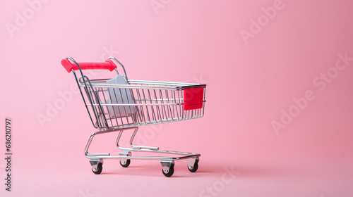 ピンクの背景に赤のショッピングカートのミニチュア