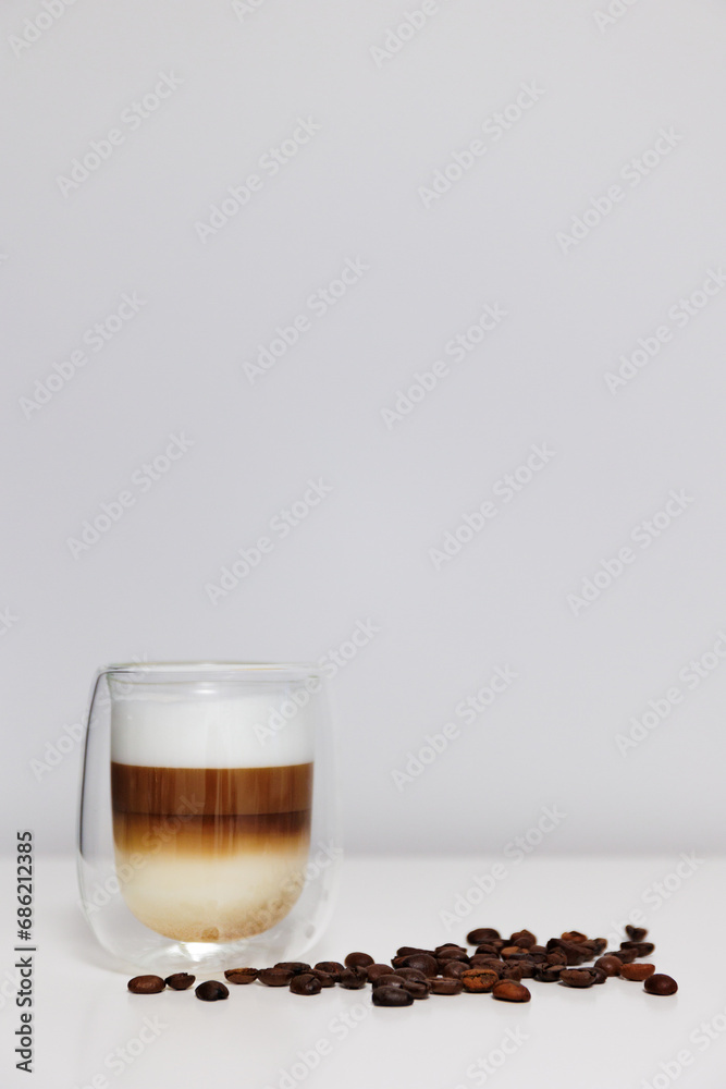 close up of glass of fresh latte coffee with coffee beans on white table and copy space close up of glass of fresh latte coffee with coffee beans on white table and copy space