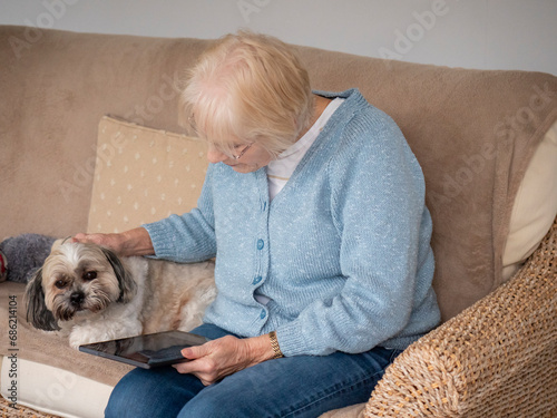 An 80 year old lady sitting using her Tablet for online shopping.