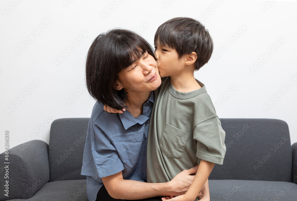 Portrait of happy Asian woman and her little son hugging and sitting on sofa at home. Portrait of happy Asian woman and her little son hugging and sitting on sofa at home.
