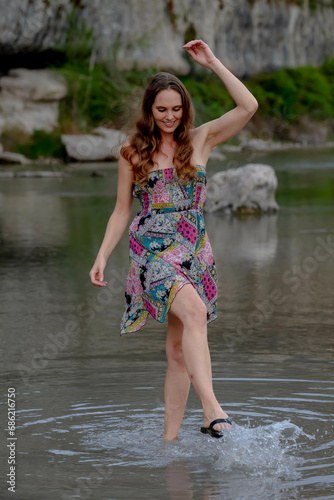 Fototapeta Naklejka Na Ścianę i Meble -  A Lovely Brunette Female Model Enjoys The Summer Weather On The Shores Of A Local Lake