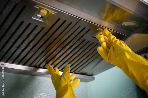 Housekeeping hands trying to removing a filters from cooker hood for cleaning it. photo